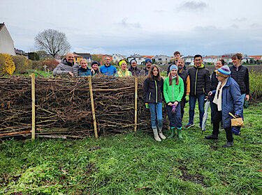 Gruppenbild an der Benjeshecke aus aufgeschichteten Ästen und Zweigen