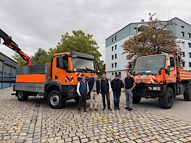 Gruppenbild vor dem neuen und einem alten LWK im Hof des Bauhofs