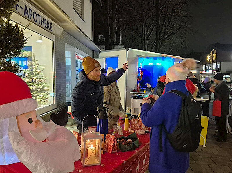 Adventlich geschmückter Tisch vor der Apotheke und Besucher:innen